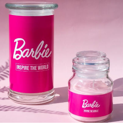 Kollektionsbild der Barbie-Duftkerzen mit der ‚Inspire the World‘ (400g) Duftkerze in klein (110g) und groß (400g) – Pinke Glas mit weißer Schrift, vegane Lizenzkerze als Deko- oder Geschenkidee für Barbie-Fans.
