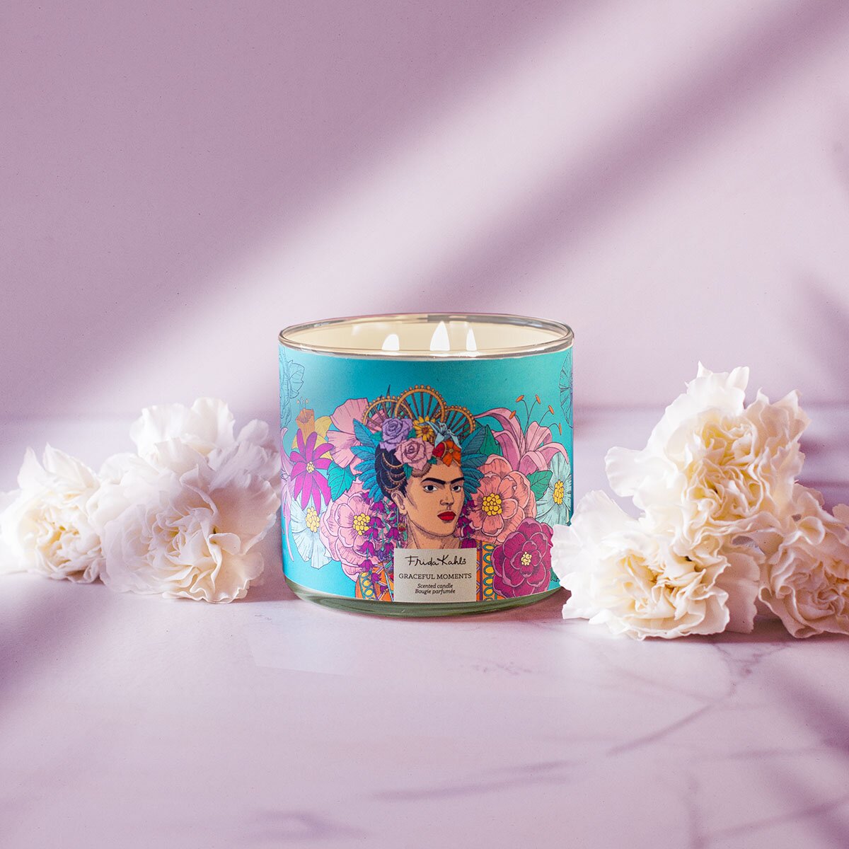 Frida Kahlo Duftkerze Graceful Moments 400g – brennende Design-Duftkerze mit Frida-Porträt, weißen Blüten und lilafarbenem Hintergrund, edles Wohnaccessoire & Geschenkidee.