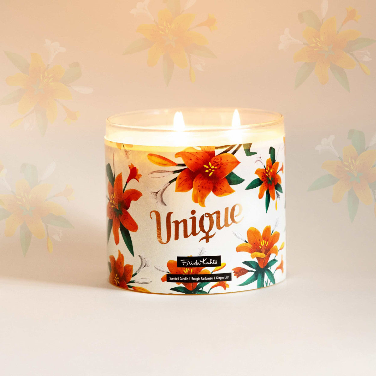 Frida Kahlo Duftkerze ‚Unique‘ (400g) – Moodbild der offiziellen Lizenzkerze  im blumigen Design. Die kunstvoll verzierte Kerze steht frontal auf einem weißen Untergrund. Der bronzene Deckel wurde abgenommen und dir drei Baumwolldochte brennen  – dekorative Duftkerze und ideale Geschenkidee für unter 20 €.