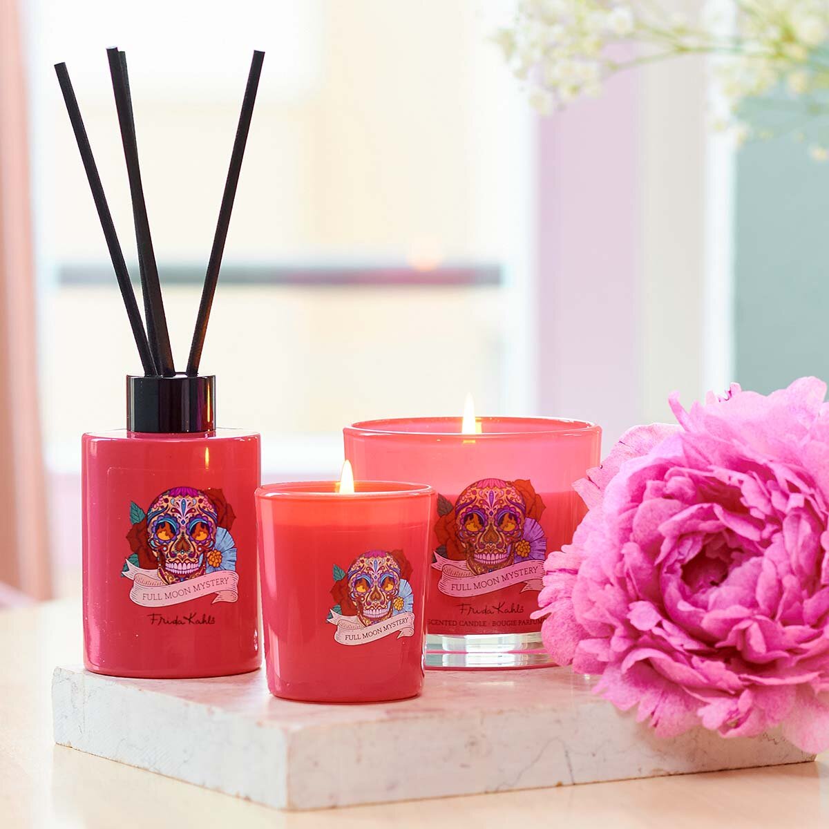 Frida Kahlo Full Moon Mystery Kollektion Duftstäbchen zusammen mit Duftkerzen. Stilvoll angerichtet auf einem Mamorstein mit rosa Blüte. Perfekte Raumerfrischung, die eine elegante und hochwertige Dekoration darstellen.