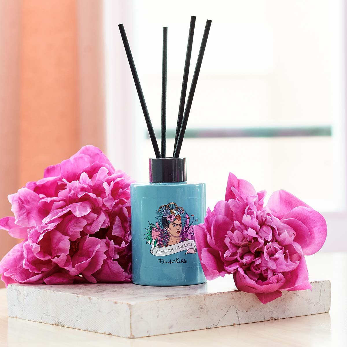 Frida Kahlo Graceful Moments Duftstäbchen 100ml. Elegant platziert auf einem Mamorstein mit pinken Blüten. Perfekte Raumerfrischung, die eine elegante und hochwertige Dekoration darstellen.