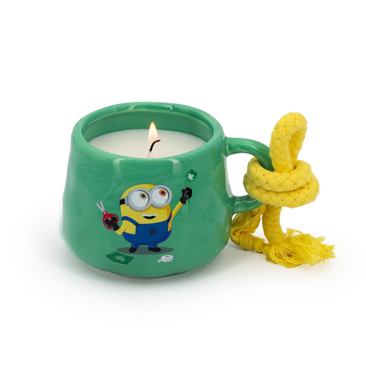 Minions Duftkerze Bob (200g) in grüner Keramiktasse mit gelber Kordel. Als Motiv sieht man den Minion Bob, der in der einen Hand eine Schere hält und in der anderen ein vierblättriges Kleeblatt. Das Wachs ist weiß und der Docht brennt.