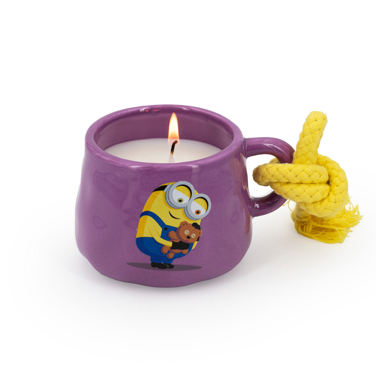 Minions Duftkerze Bob & Tim (200g) in lila Keramiktasse mit gelber Kordel. Als Motiv auf der Tasse ist Bob abgebildete, der sein Kuschelbären Tim umarmt. Das Wachs ist weiß und der Docht brennt.