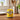 Gelbe Minions Duftkerze "Stuart" mit der Sammeltasse steht in einer Küche auf der Arbeitsplatte. Die Kerze brennt ruhig ab. 
