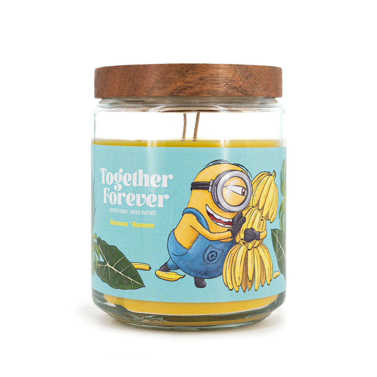 Minions XXL-Duftkerze ‚Together Forever‘ (510g) – Vorderseite der offiziellen Lizenzkerze mit farbenfrohem Minions-Motiv, Palmenblättern und einer Bananenstaude. Vegane Duftkerze im Glas als stylische Deko oder Geschenk für Fans.