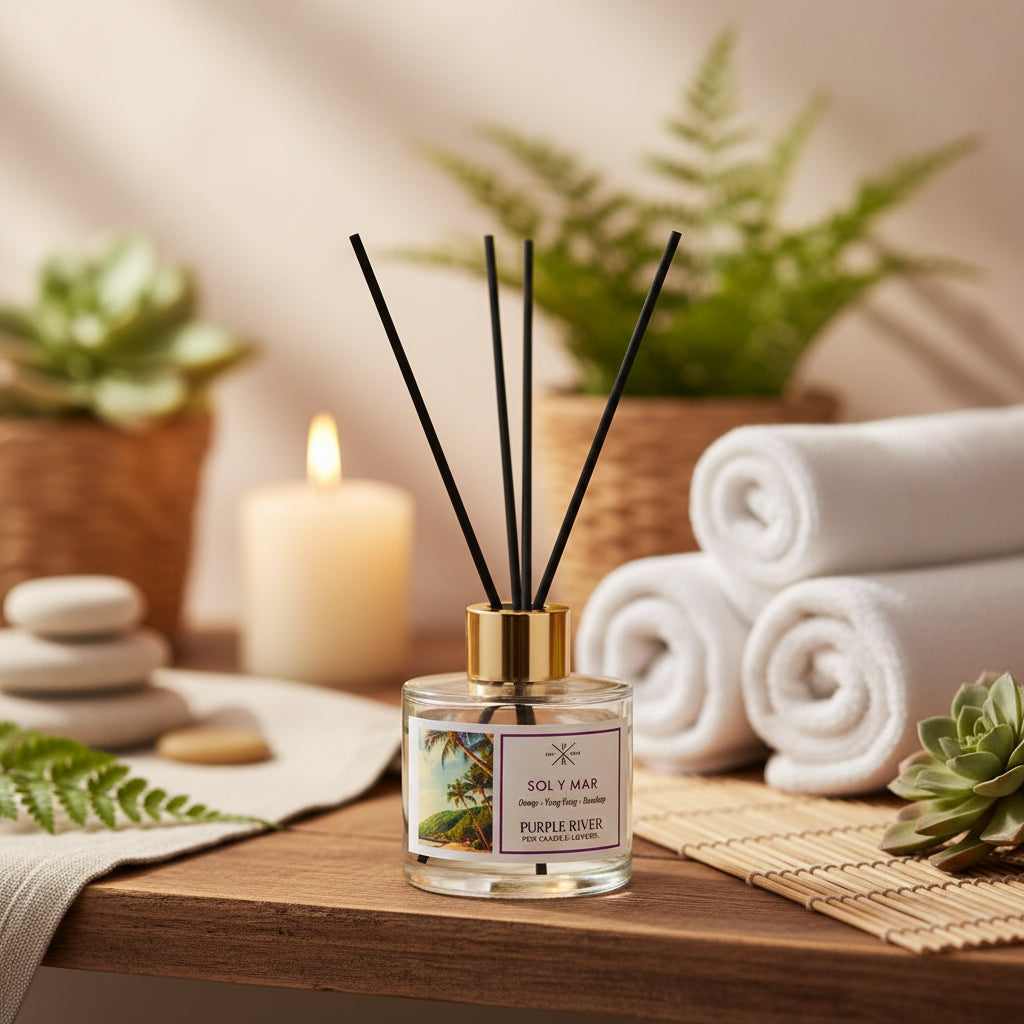 Purple River Raumduft (100 ml) mit schwarzen Schilfstäbchen und goldener Kappe in einem Wellness-Bereich, umgeben von Grünpflanzen, weißen Handtüchern und einer brennenden Kerze; hochwertiger Duft mit bis zu 6 Wochen Duftdauer, ideal als stilvolle Dekoration und luxuriöses Wellness-Geschenk, gefertigt in Deutschland.